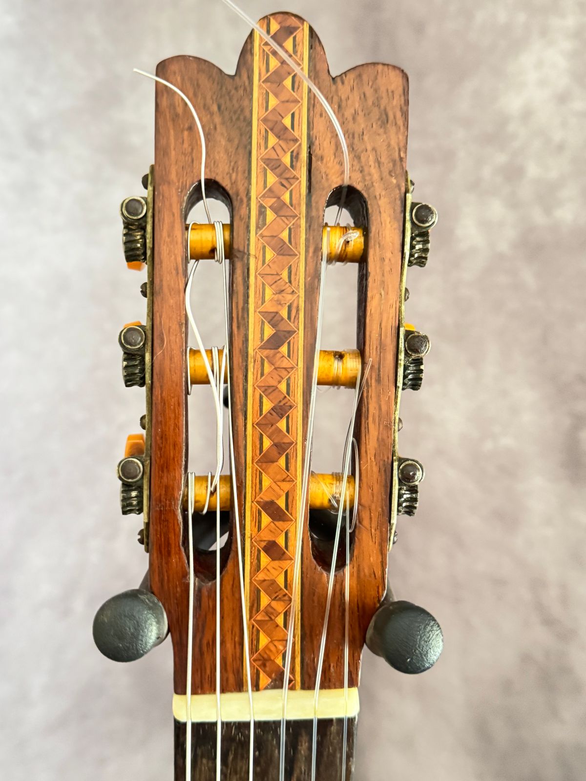 Headstock front showing hand-inlaid marquetry strip of alternating diamond lozenges